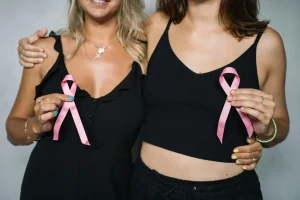 Two women hold up breast cancer awareness ribbons signifying the importance of annual mammograms